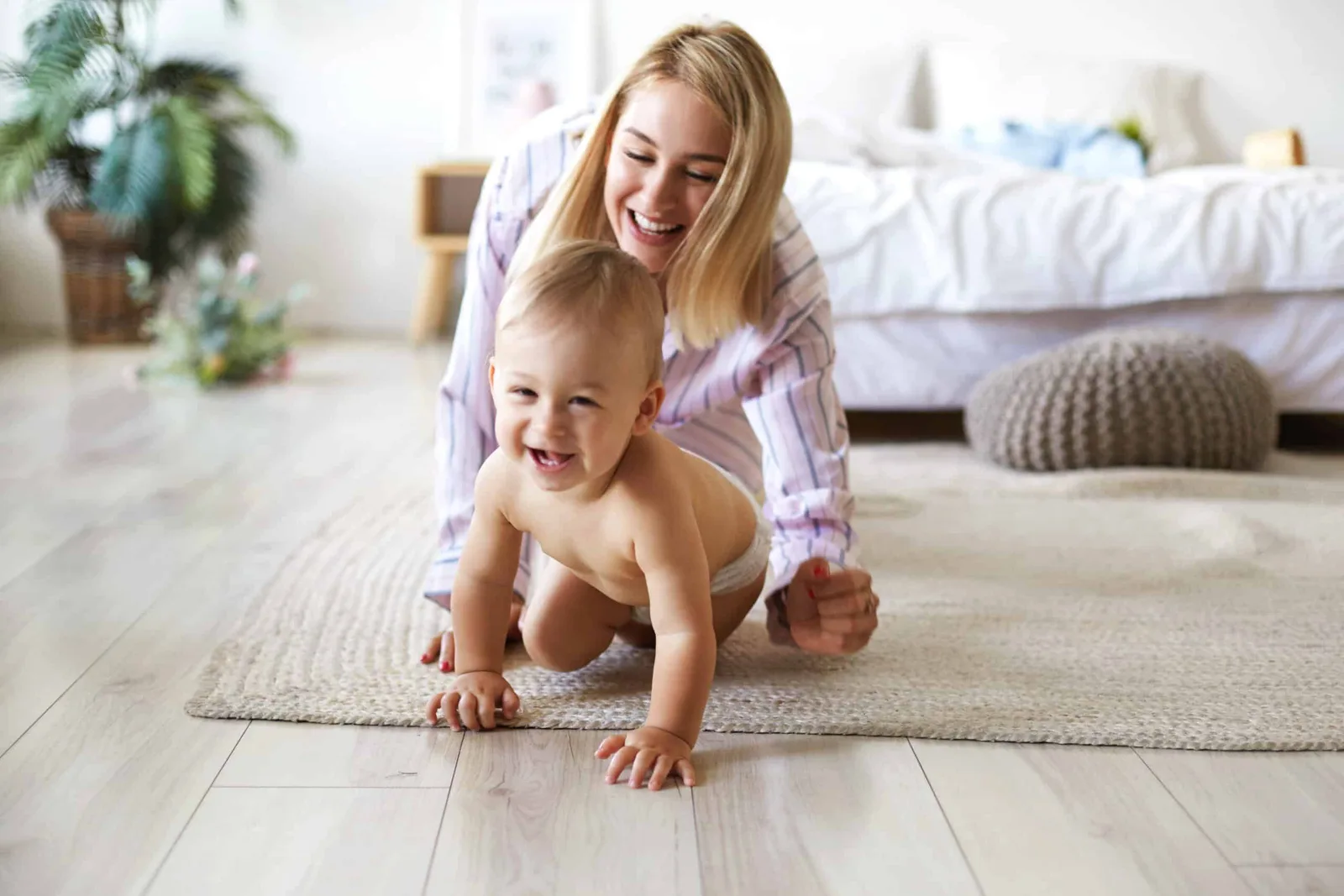 Mom and laughing baby crawling on a new luxury vinyl plank floor in an Oklahoma City bedroom
