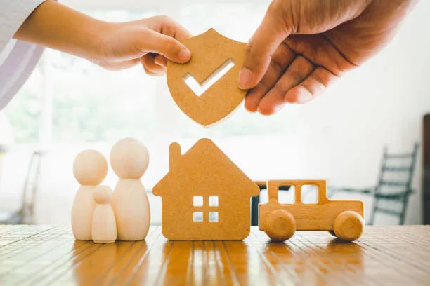 Hands holding a protective checkmark shield over a wooden house and family — the Floors To You lifetime installation warranty